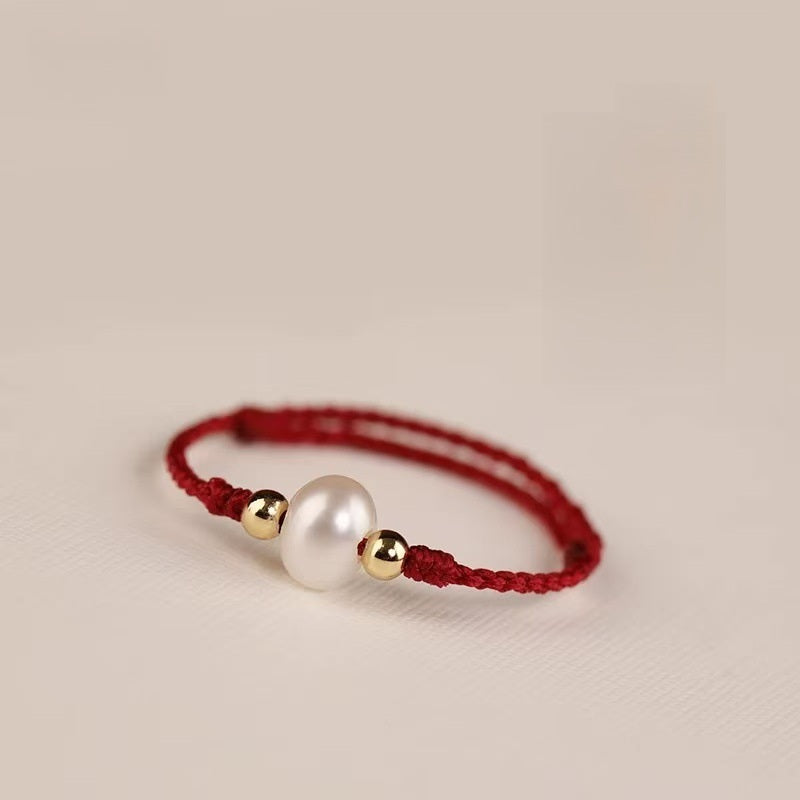 Pearl Cord Ring – Red braided cord ring with white pearl center and gold beads on cream background