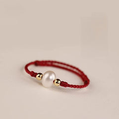 Pearl Cord Ring – Red braided cord ring with white pearl center and gold beads on cream background