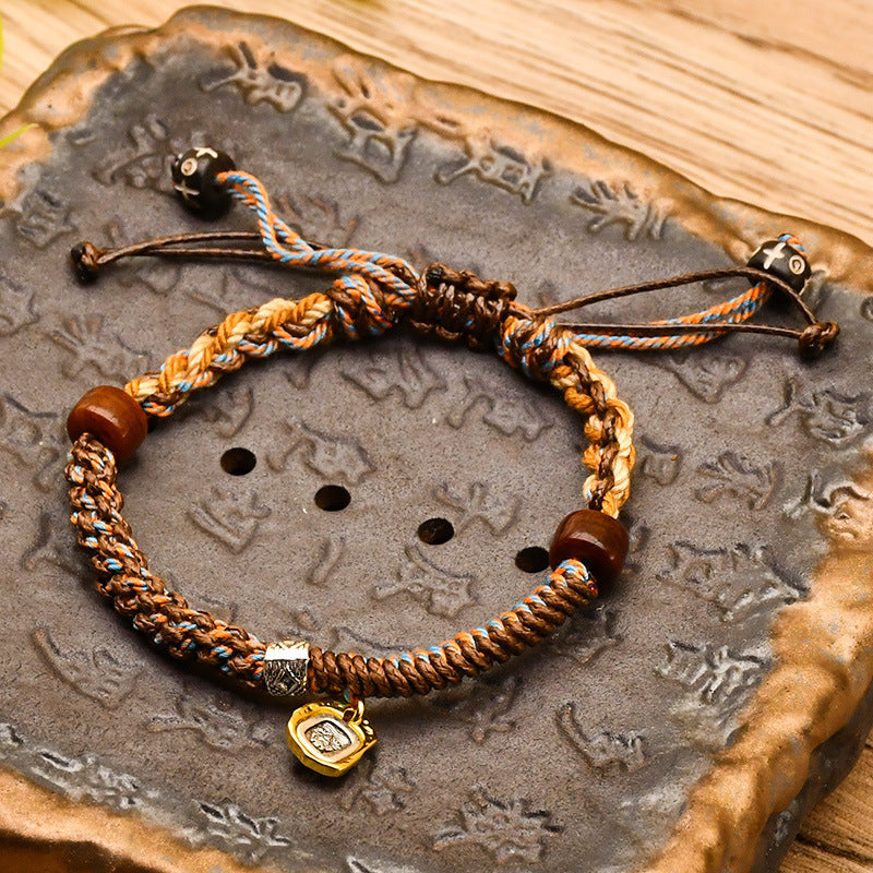 Tibetan Cord Bracelet – blue woven cord with wood beads and gold charm on engraved stone, balance bracelet