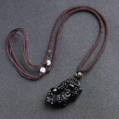 Obsidian Pixiu Necklace – Brown braided cord with obsidian pixiu pendant, white bead adjusters on gray