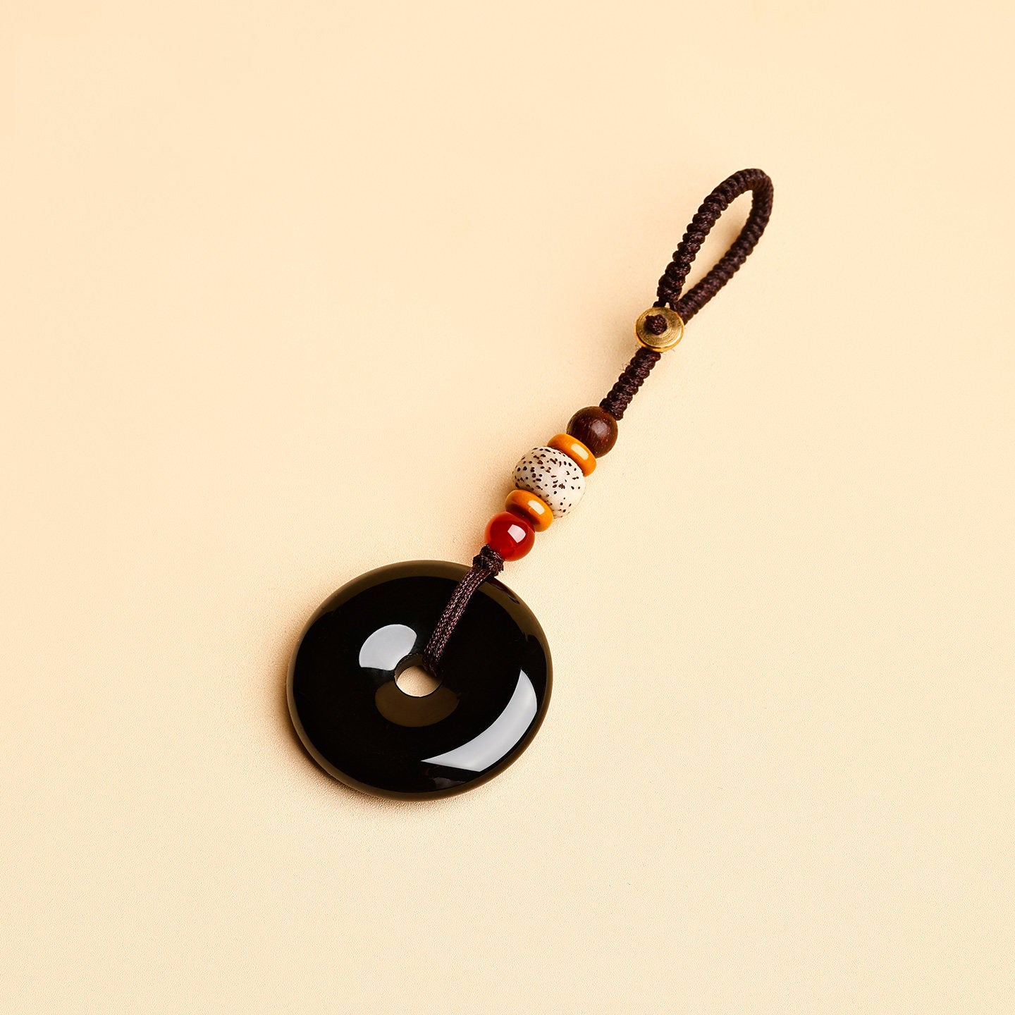 Jade Keychain Pendant – Black jade donut pendant with brown cord and red agate beads on beige, protection charm