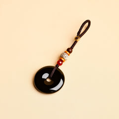 Jade Keychain Pendant – Black jade donut pendant with brown cord and red agate beads on beige, protection charm