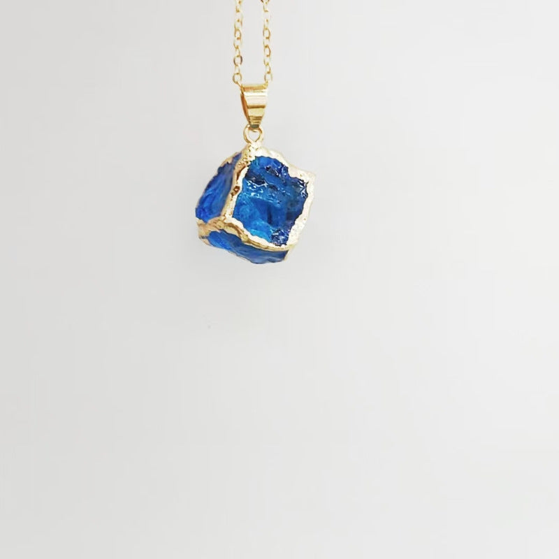 Gemstone Chip Pendant – Blue sapphire-tone raw crystal cube in gold frame on chain, white background