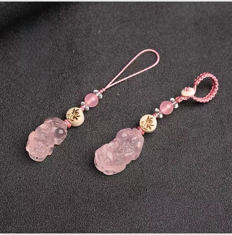 Quartz Fox Keychain – pair of pink crystal pixiu pendants with pink cord and lotus beads on dark textured background