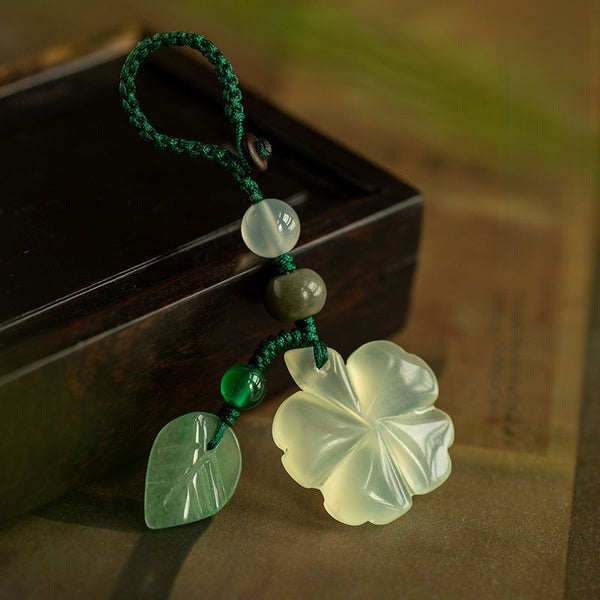 Jade Clover Keychain – clover with woven green loop and leaf charm resting on dark wood