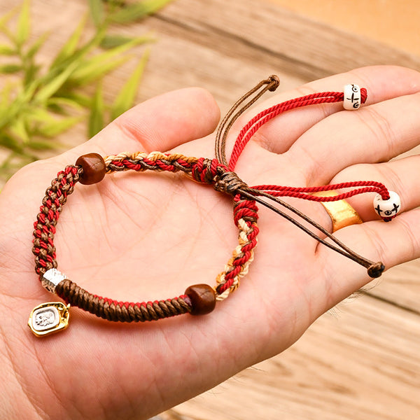 Tibetan Cord Bracelet – red cord worn on hand showing wood beads and gold charm, spiritual jewelry