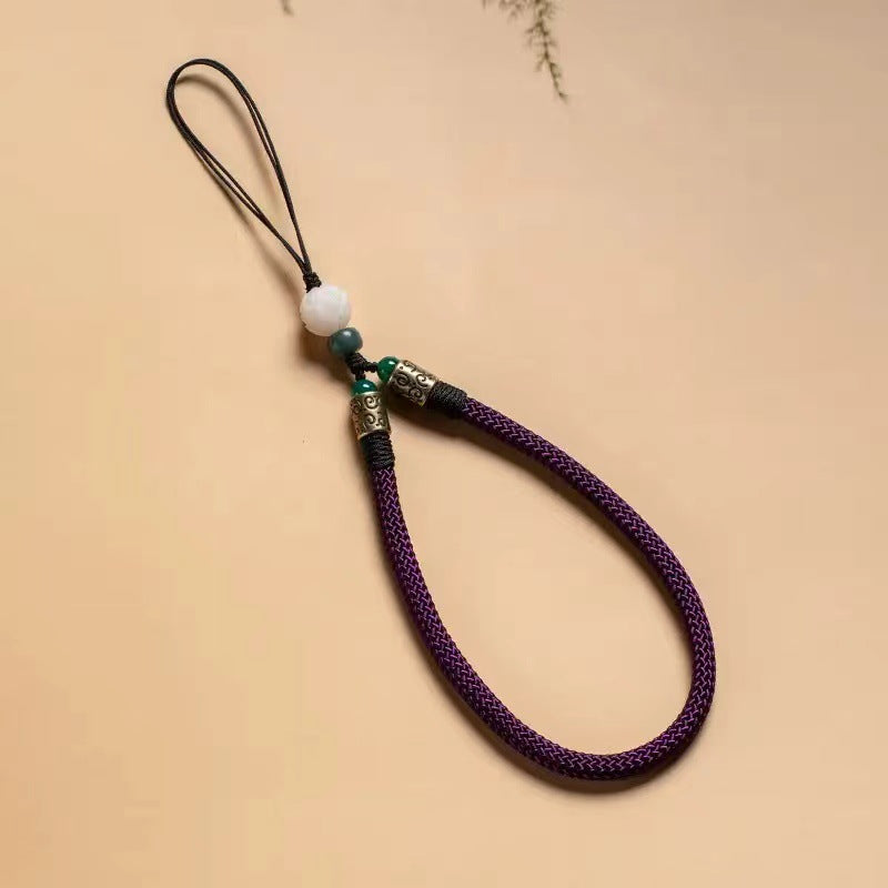 Lotus Bodhi Lanyard – Deep purple braided lanyard with white lotus bead and bronze accents on neutral background, calm phone strap