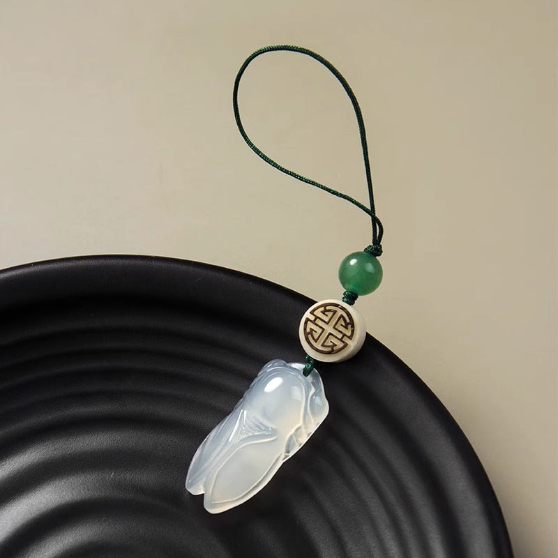 Chalcedony Cicada Keychain – carved cicada pendant with green cord and fortune bead on black plate