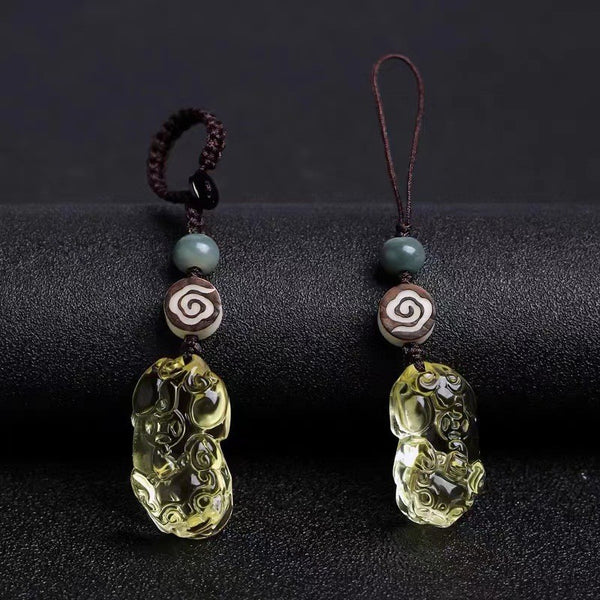 Quartz Fox Keychain – two lemon yellow crystal pixiu pendants with brown cord and cloud pattern beads on black surface