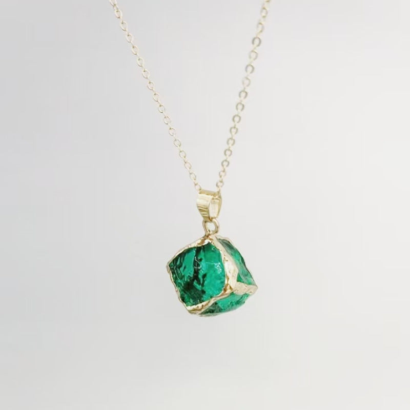 Gemstone Chip Pendant – Green emerald-tone raw crystal cube in gold rim on chain, white background