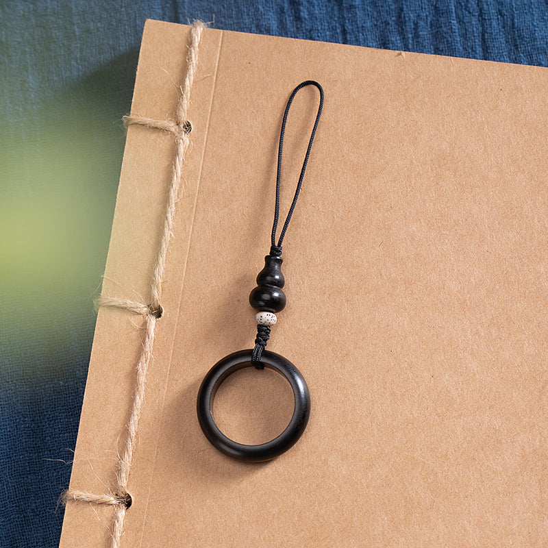 Sandalwood Phone Grip – Black wood ring grip with white spotted bead on handmade book, minimalist phone anti-drop strap