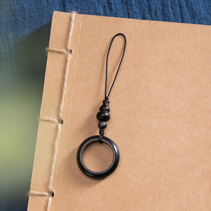 Sandalwood Phone Grip – Ebony black ring lanyard with patterned bead on bound journal, sleek wooden phone accessory