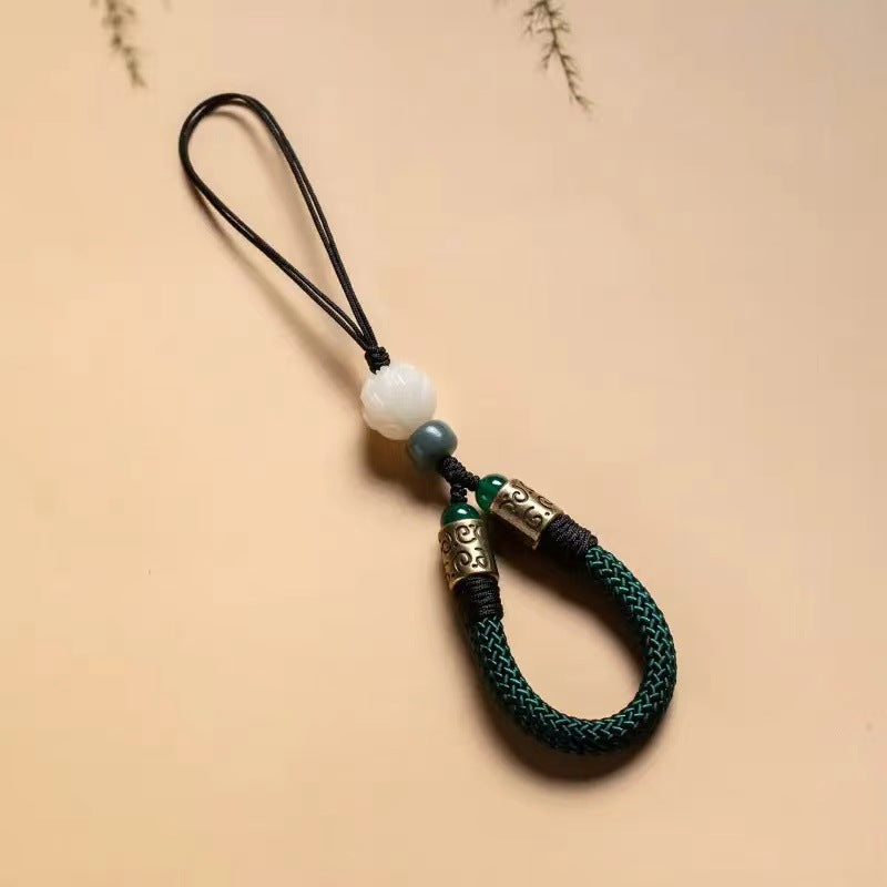 Lotus Bodhi Lanyard – Green braided wrist strap with white lotus bodhi bead and bronze fittings on beige background, Zen phone accessory