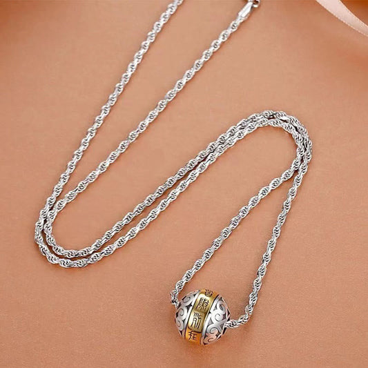 Taoist Nine-Character Mantra Copper Pendant – Silver rope chain with gold-character rotating bead pendant, smooth beige tan surface top-down angled view
