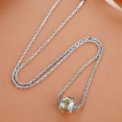 Taoist Nine-Character Mantra Copper Pendant – Silver rope chain with gold-character rotating bead pendant, smooth beige tan surface top-down angled view