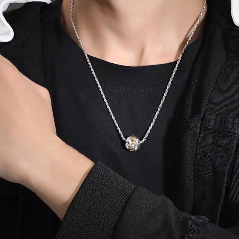 Taoist Nine-Character Mantra Copper Pendant – Silver rope chain with cylindrical filigree pendant worn on black crew neck under denim jacket, lifestyle frontal