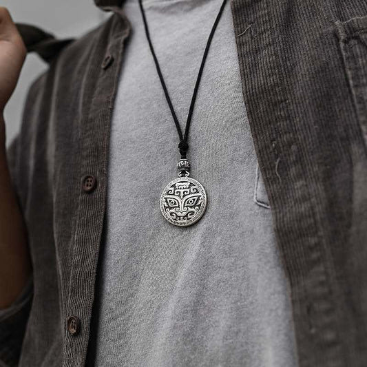 Taotie Copper Wealth Necklace – Silver taotie mask pendant worn on gray shirt with layered brown corduroy, chest-level lifestyle frontal