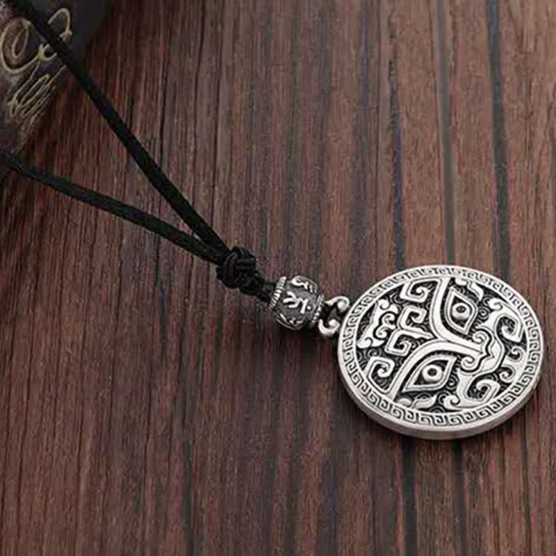 Taotie Copper Wealth Necklace – Silver pendant with Celtic knotwork spiral designs on black cord, dark brown wood grain overhead flat lay