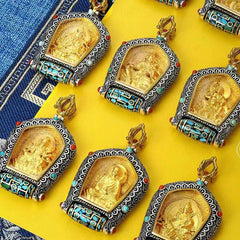 Tibetan Zodiac Buddha Dzi Bead Necklace – Gold Mahasattva Bodhisattva pendant in silver cloud-pattern frame with turquoise coral accents and prayer wheel, brown wood backdrop