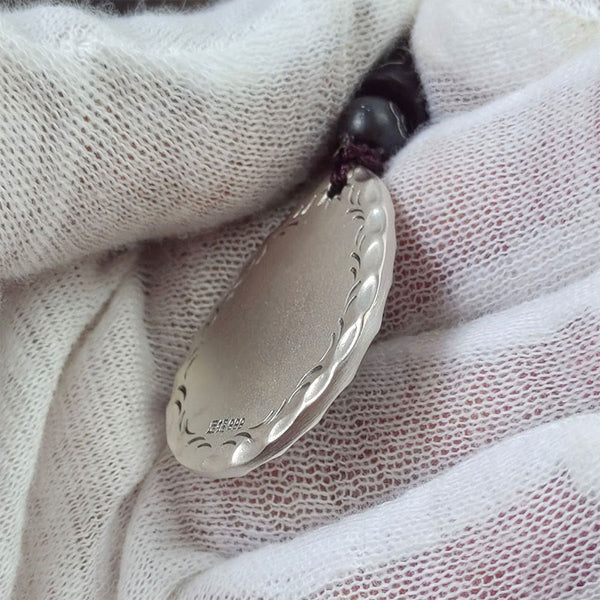 Yin Yang Bagua Water Drop Necklace – 999 silver oval pendant with scalloped braided border engraving and purity mark on black cord, white glove fabric overhead