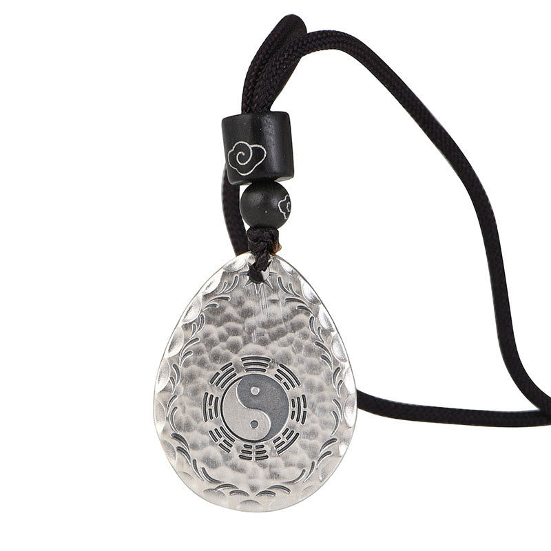 Yin Yang Bagua Water Drop Necklace – Silver teardrop pendant with yin-yang bagua and wave patterns on black cord with wooden cloud-accent beads, white background angled