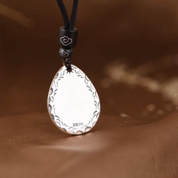 Yin Yang Bagua Water Drop Necklace – 999 silver teardrop pendant with hammered texture and wave border on black cord with cloud-accent beads, brown fabric bokeh