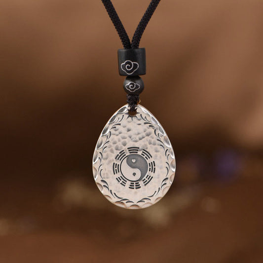 Yin Yang Bagua Water Drop Necklace – Silver teardrop pendant with yin-yang and bagua symbols on black cord with cloud-engraved beads, brown background