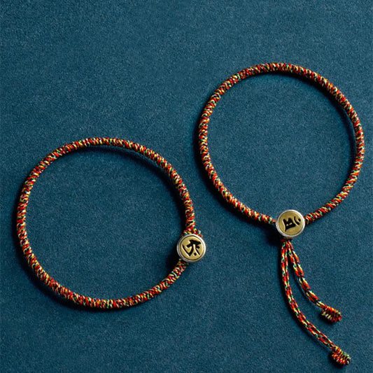 Chinese Zodiac Natal Buddha Bracelet – Two red green gold cord bracelets with engraved zodiac charms, top-down flat lay on teal background