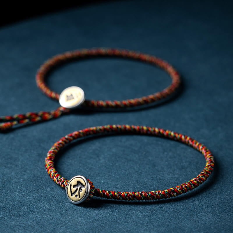 Chinese Zodiac Natal Buddha Bracelet – Two multicolor braided cord bracelets with metal zodiac symbol clasps, dark blue textured background