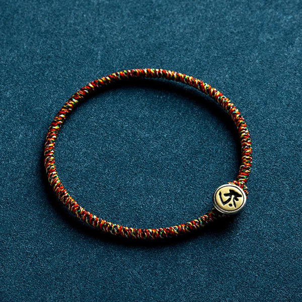Braided cord bracelet with decorative bead, flat lay