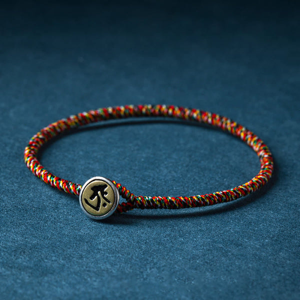 Braided cord bracelet with engraved charm, angled view