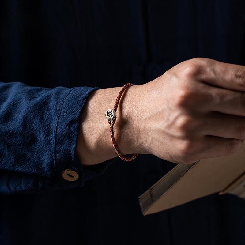 Chinese Zodiac Natal Buddha Bracelet – Multicolor cord with silver-toned zodiac charm worn on wrist, dark navy lifestyle photo